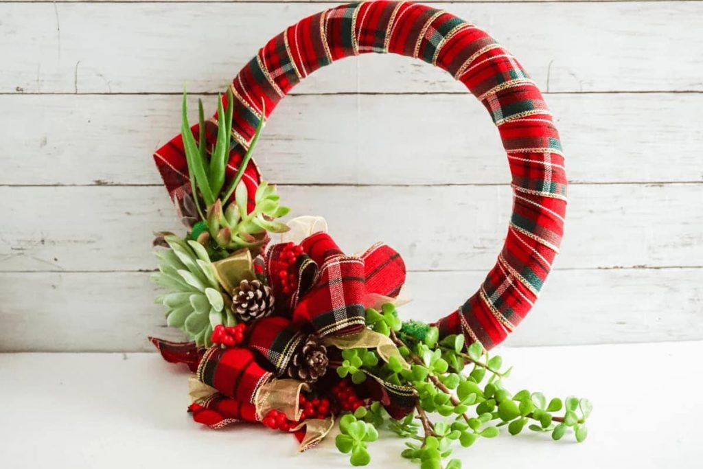 living succulent secured to red plaid wrapped wreath with large red and gold plaid bow